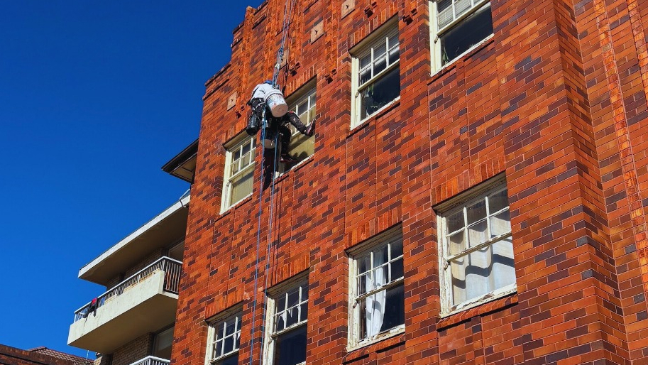 rope access painter doing painting work on strata building exterior